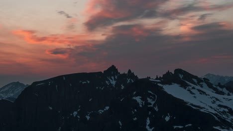 time lapse of a beautiful scenery at the top of snow covered mountains during sunset as clouds pass over the mountains.