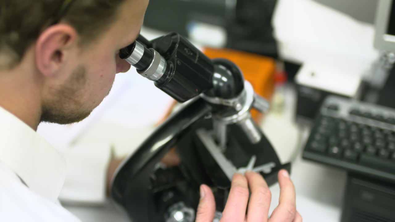 Man Looking Through a Microscope in a Laboratory