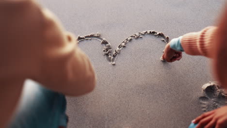 hands, couple and heart in the sand at the beach