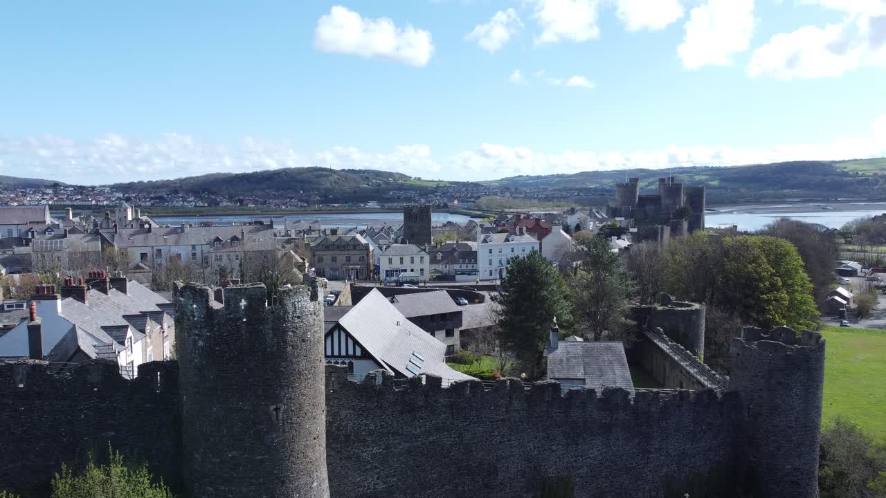 Cottage vacanze gallesi racchiusi tra le mura merlate in pietra del castello di Conwy, ripresa aerea con lento avvicinamento.