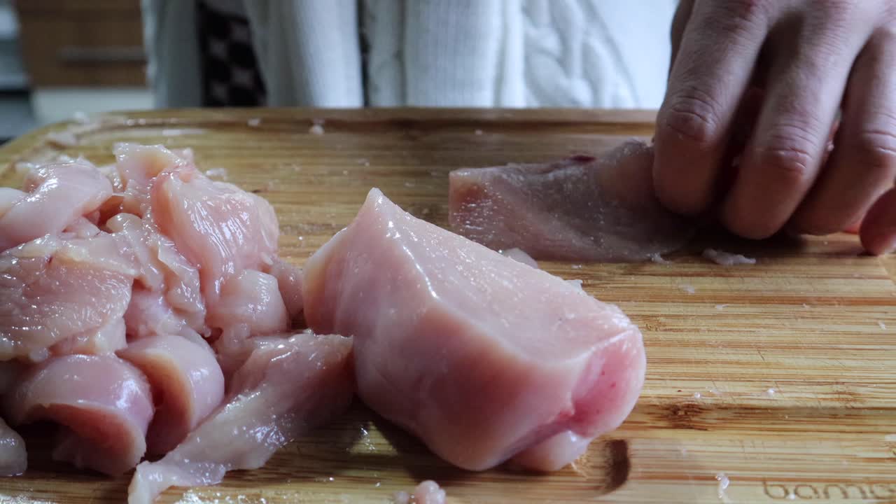 Hands Cutting Fresh Chicken Meat Fillet On Wooden Chopping Board In The Kitchen - close up