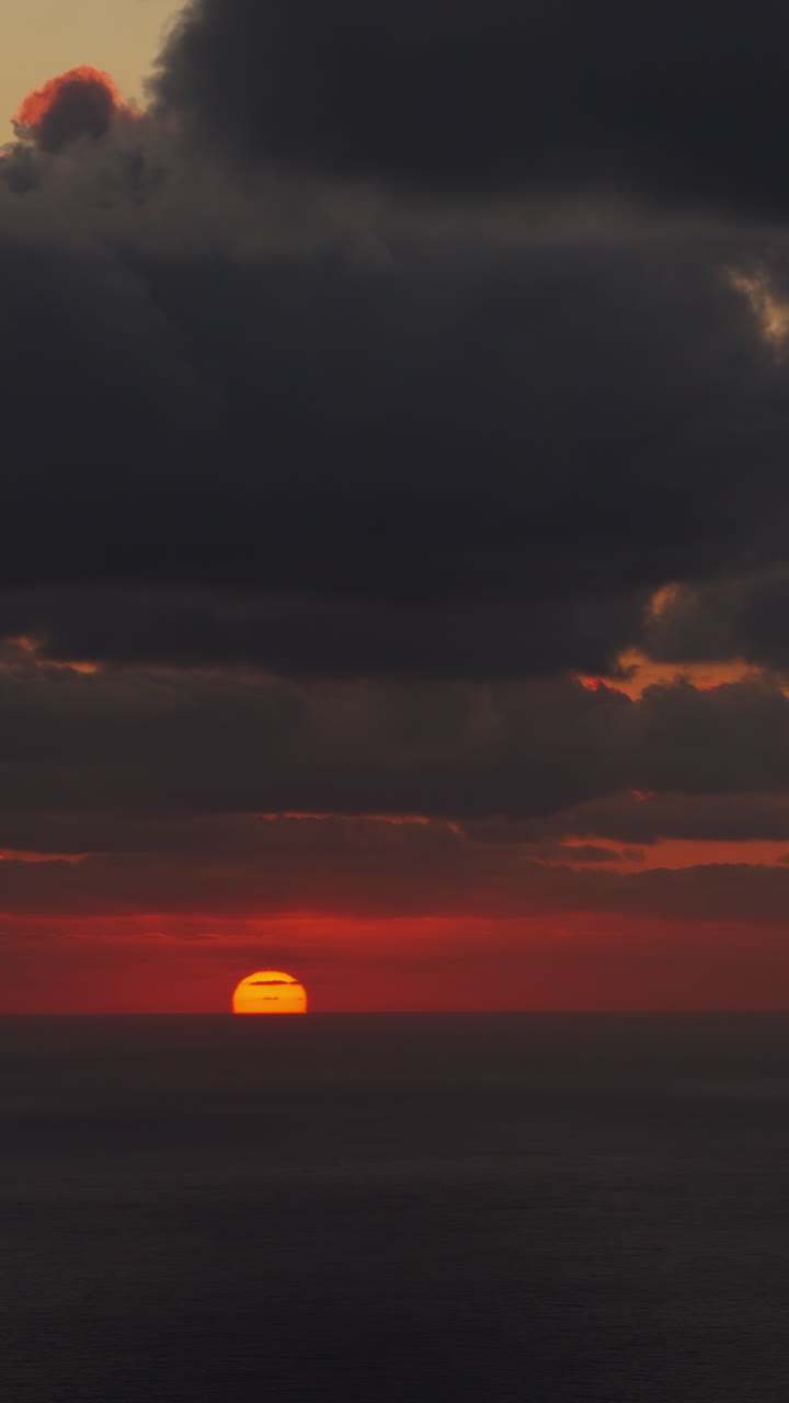 Drohnenaufnahme aus der Luft eines goldenen Sonnenuntergangs, der sich auf dem ruhigen Mittelmeer spiegelt. Vertikal.