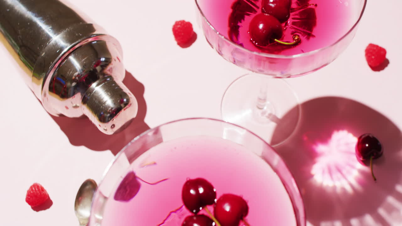 Foto close-up minuman dengan ceri dan shaker di atas latar belakang putih
