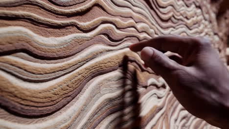 hand touching layered rock texture