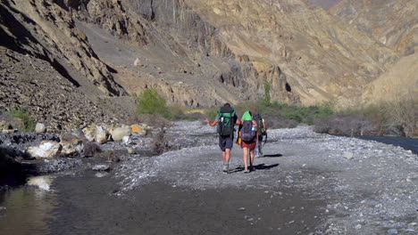 un grupo de excursionistas caminando en un lecho de río seco en las montañas