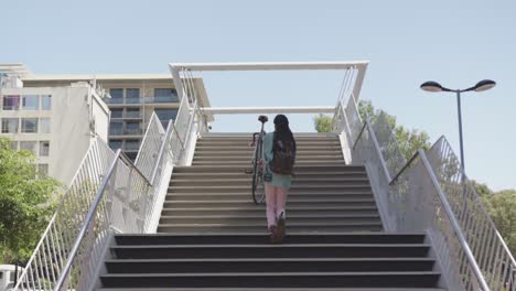 mixed race man climbing stairs with a bike