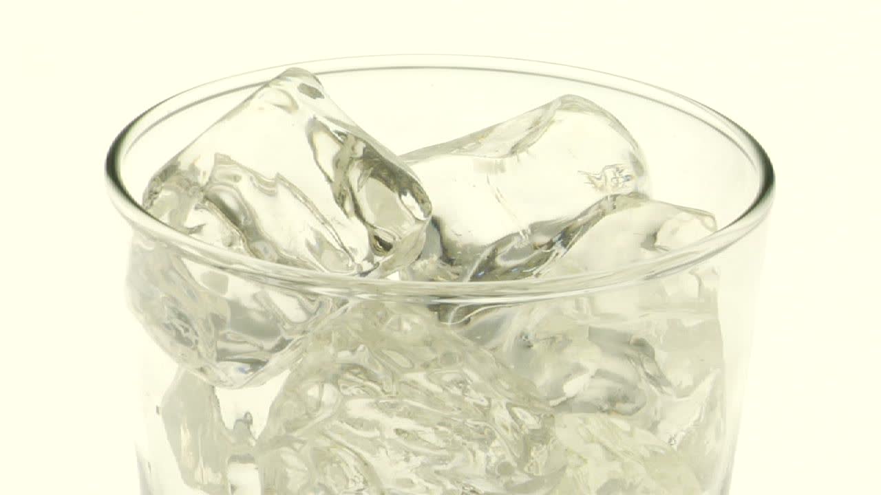 투명한 탄산 액체가 얼음 위에 유리에 부어집니다.