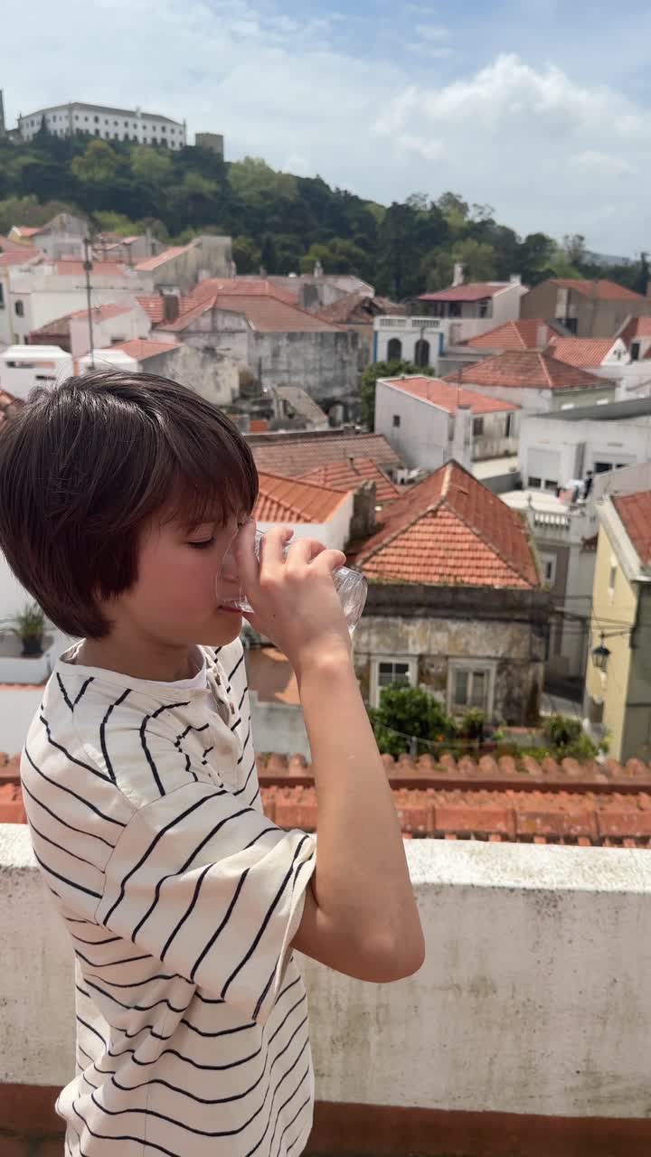 Boy Drinking on a Rooftop with City View