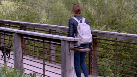 Woman-walking-small-black-dog-over-a-narrow-bridge