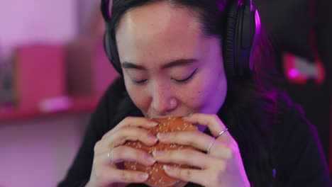 juegos, comida rápida y mujer asiática comiendo hamburguesas