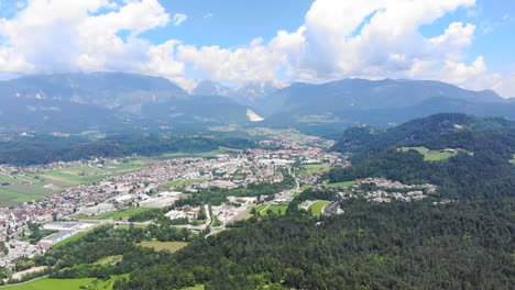 High-aerial-drone-shot-over-trees-in-countryside-approaching-mountains