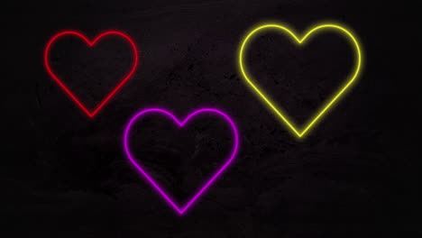 animación de corazones de neón rojo púrpura y amarillo que parpadean sobre fondo negro
