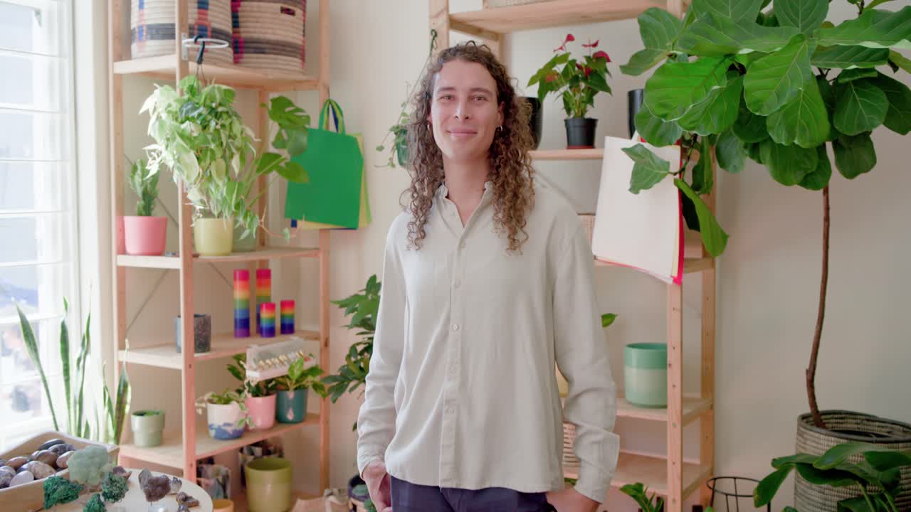 Ikke-binær person inspicerer planter nær et rundt bord i en plantebutik, bevæger sig tættere på og arrangerer potter.
