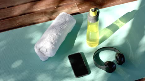 towel, bottle of water, headphones and smartphone on yoga mat at log cabin, slow motion