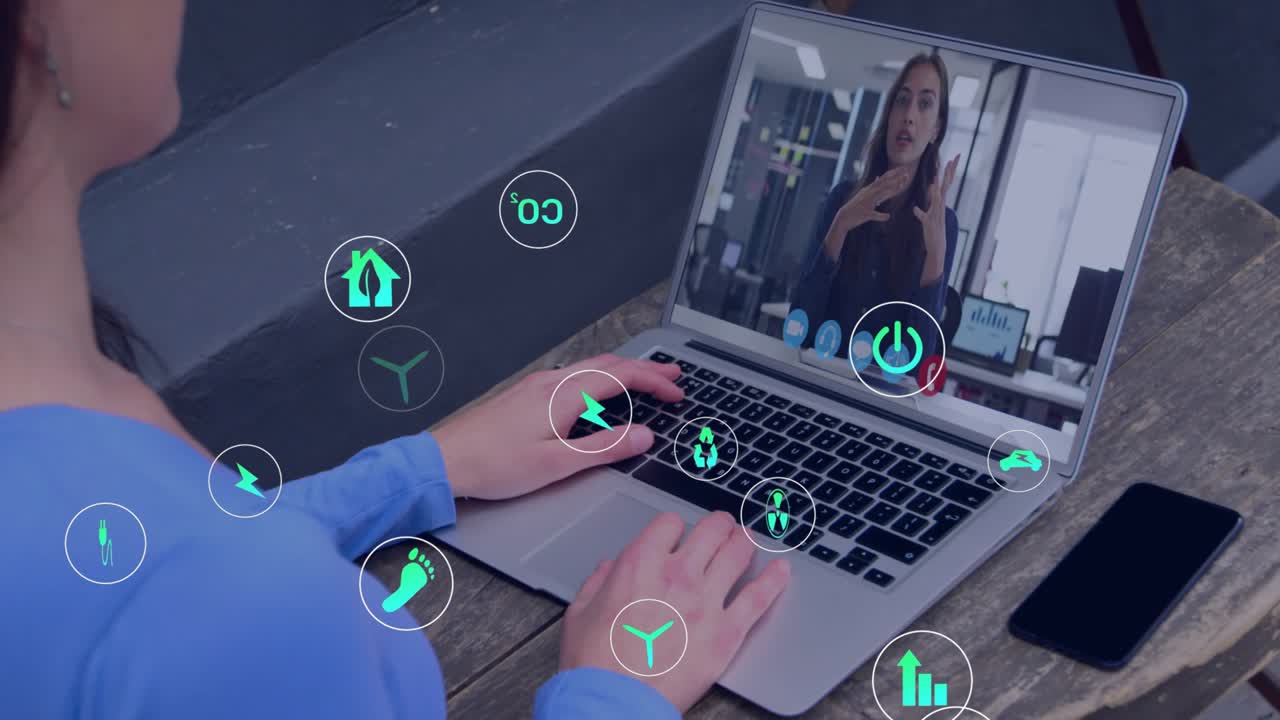 Mid-adult man tapping keyboard and listening as eco-icons appearing over laptop in business meeting