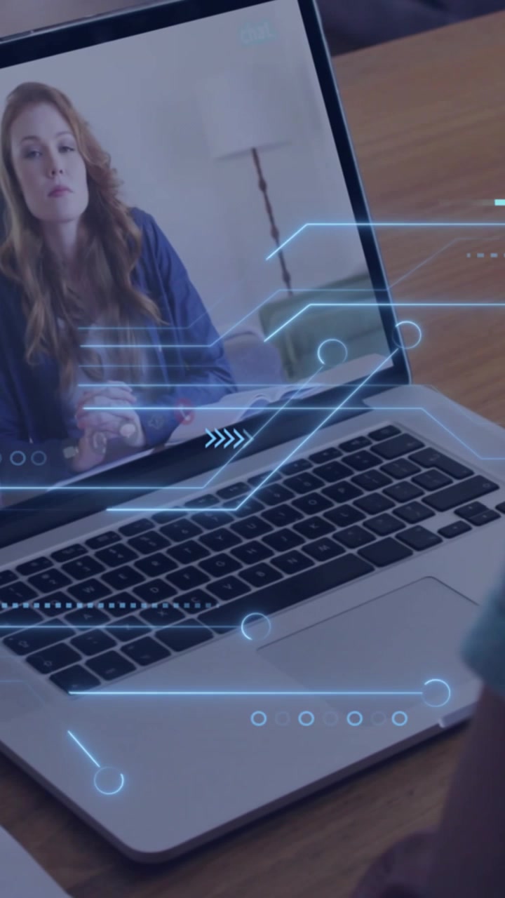 Vertikal video: Mand ved skrivebord ser på bærbar computer, opkald starter, HUD glider hen over tastaturet og viser teknologi.