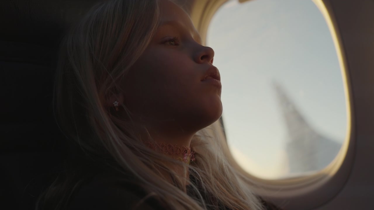 Giovane ragazza che guarda fuori dal finestrino dell'aereo durante il volo