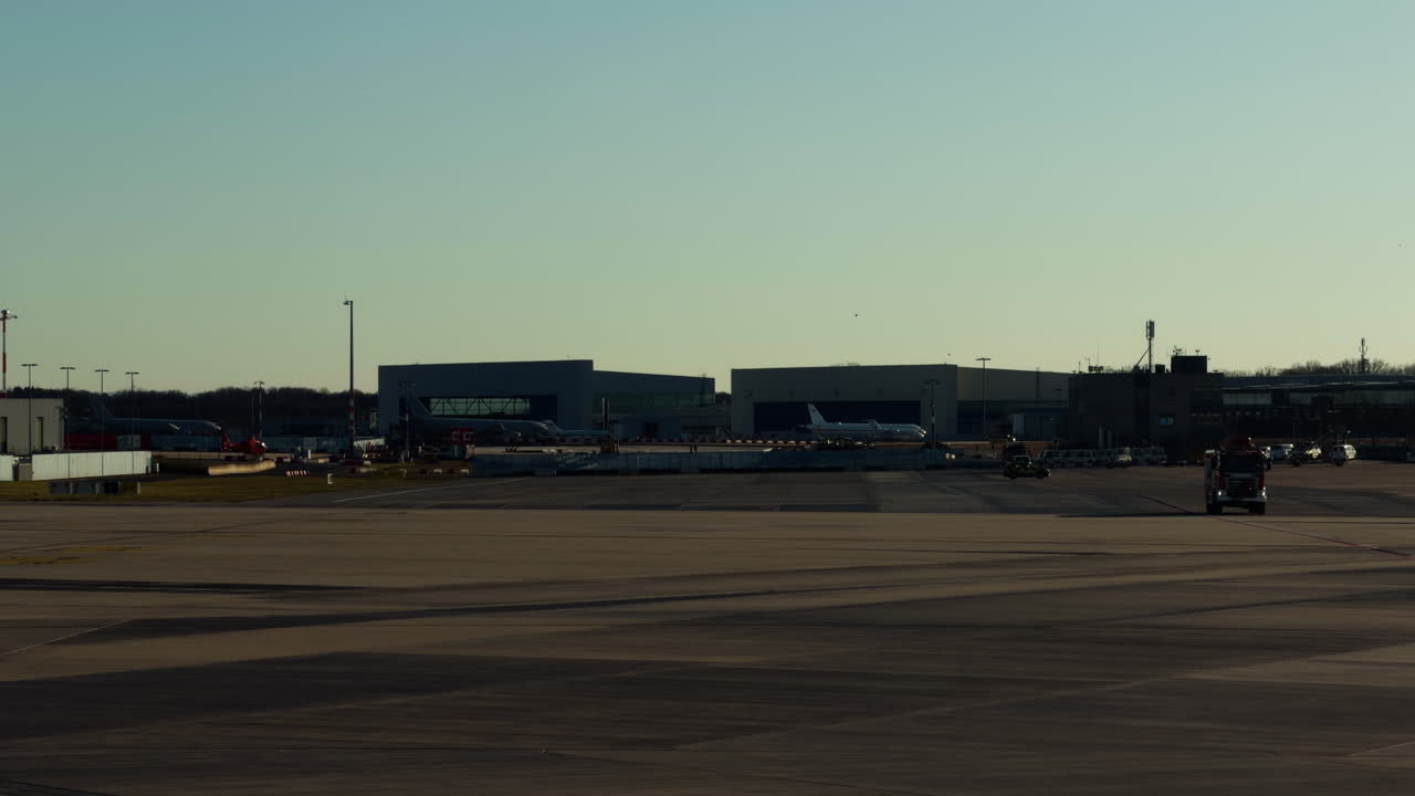 Pista aeroportuale ed edifici del terminal con aerei parcheggiati sul piazzale. Infrastruttura aeronautica con veicoli di servizio che operano su un campo d'aviazione di giorno.