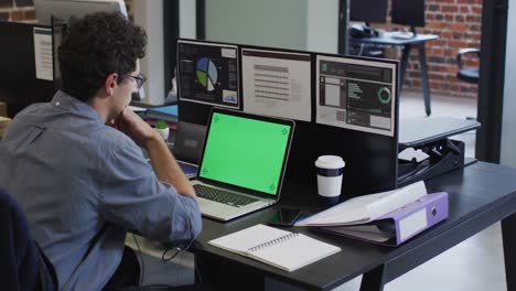 Man-using-laptop-while-sitting-on-his-desk-at-office