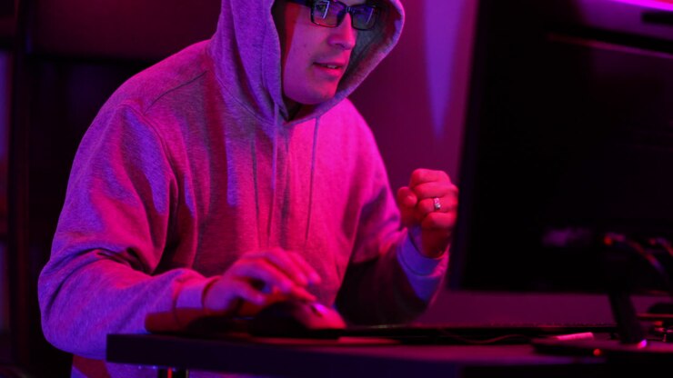 Hacker with a hooded sweathshirt and glasses successfuly hacks a computer and quickly runs off