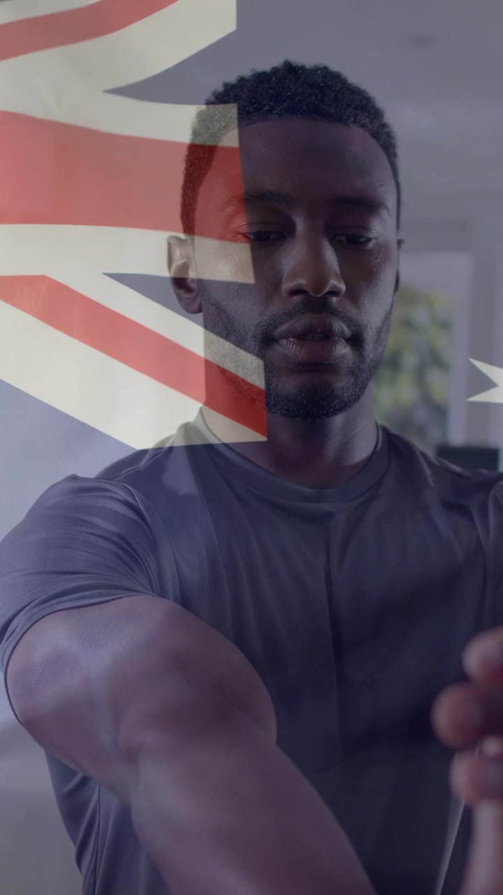 Vertikal video: Mand folder hænderne i et rum med flag-overlay, skaber en fodbold til sport.