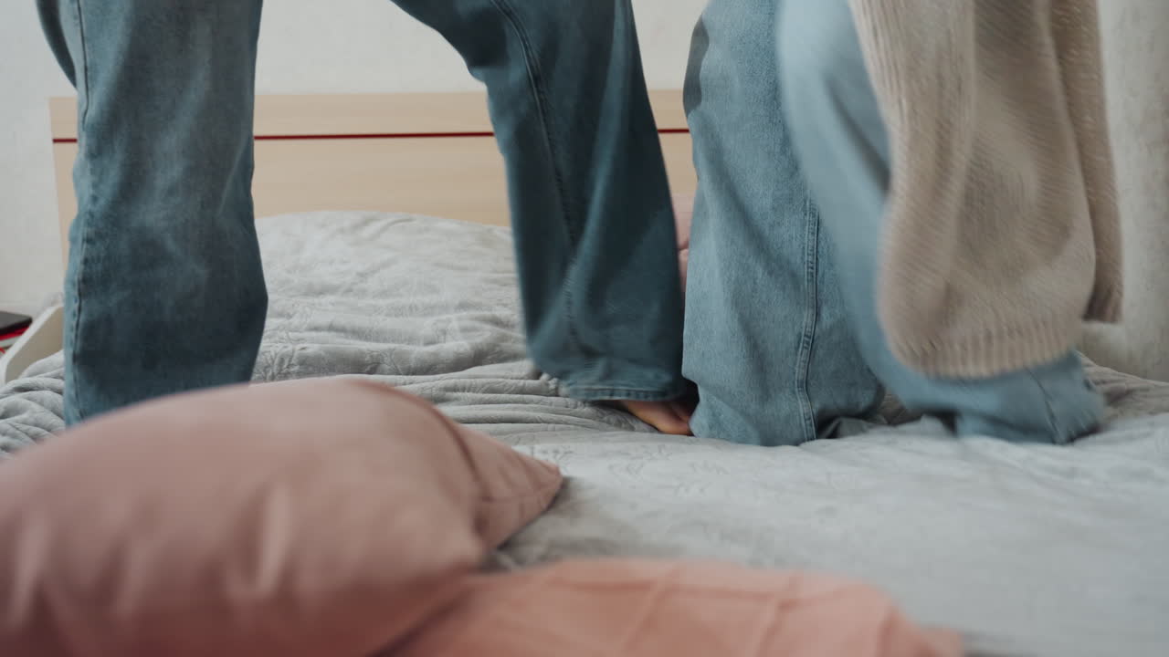 Casual Woman Jumping On Bed, Everyday Scene Of Woman In Comfortable Clothing Moving Naturally, Informal Depiction Of Woman In Jeans And Cardigan Enjoying Playful Activity On Her Cozy Bed