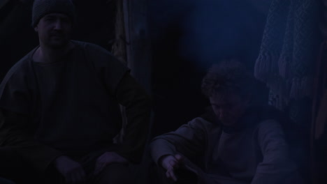 two men sitting in a dark hut at night
