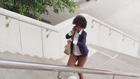 african american businesswoman walking and talking on smartphone