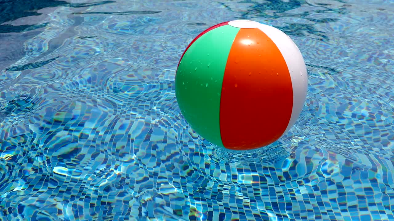 Beach ball in pool. Colorful inflatable ball floating in swimming pool.