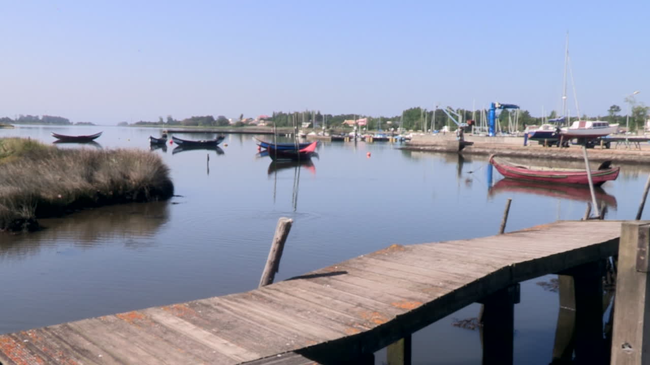 bella imagen de un puerto pesquero en el río con pasarela que entra en el río y tradicionales barcos de madera amarrados
