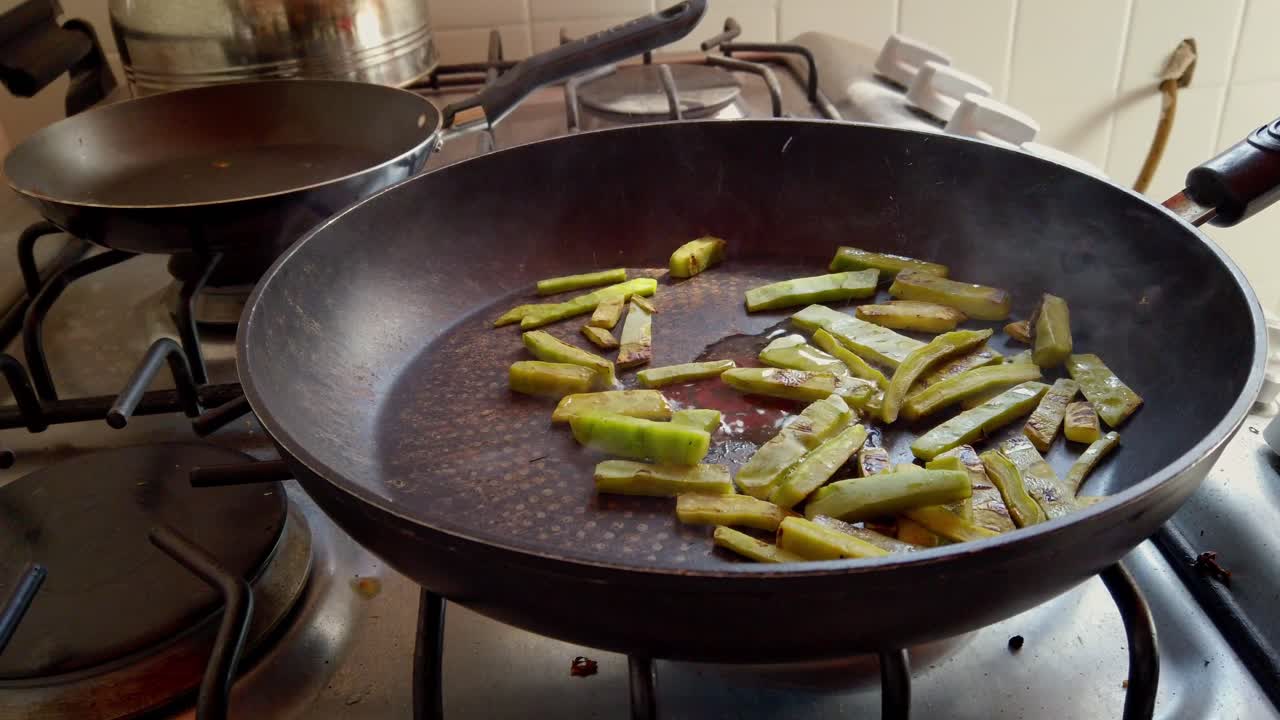 Asparagi affettati che cuociono in padella sul fornello, in un ambiente di cucina domestica.
