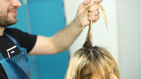 hair dresser is dyeing hair of beautiful woman in barber shop