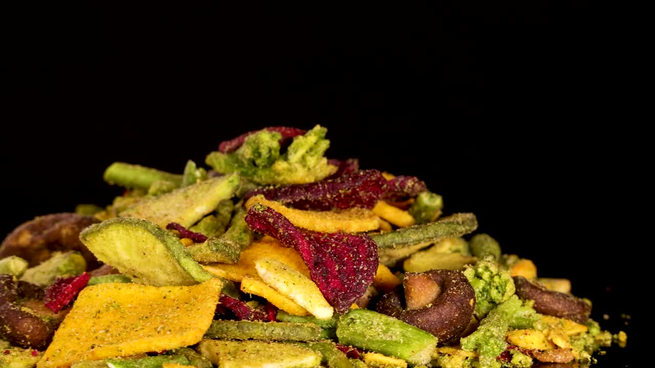 Colorful dried vegetable chips rotate under studio lighting, revealing texture and crunchy detail