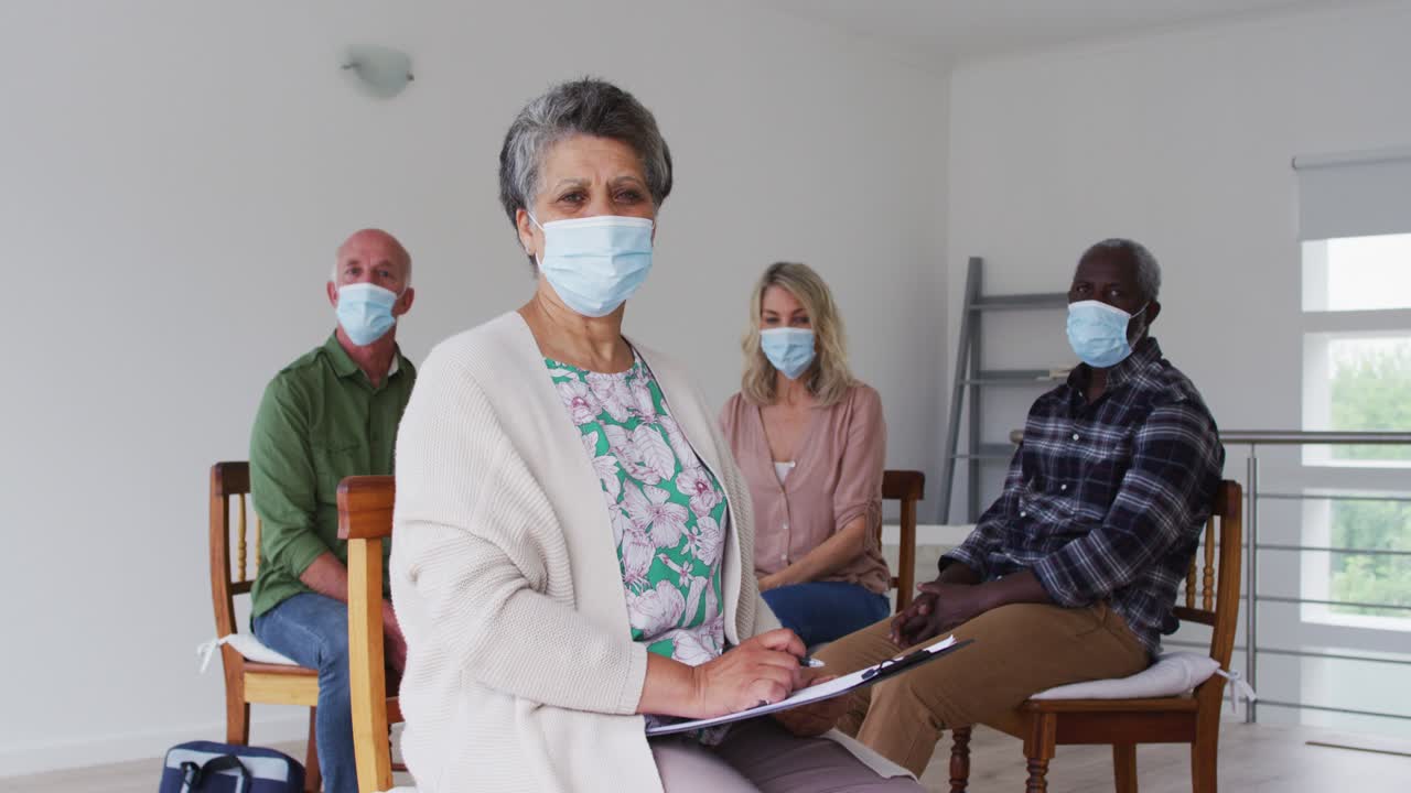 두 명의 다양한 노인 커플이 원에 앉아서 집에서 치료 대화를 나누고 카메라를 보고 있습니다.