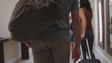 familia multigeneracional con equipaje abriendo la puerta principal y saliendo de vacaciones