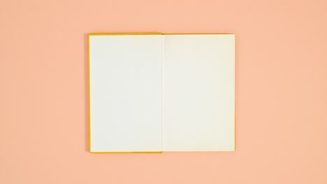 yellow hardcover book appear on orange theme and opens. stop motion