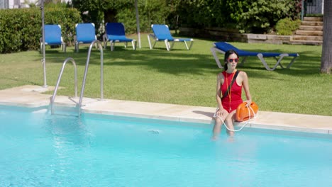 socorrista en traje de baño rojo sentado en el borde de la piscina