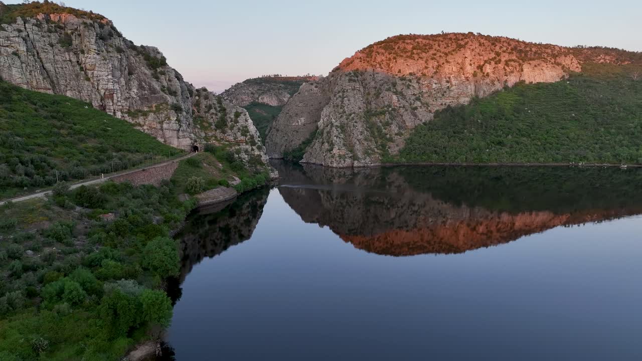 Aerial side view of Portas de Ródão, where the Tejo River flows through towering cliffs in Vila Velha de Ródão. A stunning Beira Baixa landmark with a bridge, perfect water mirror landscape.