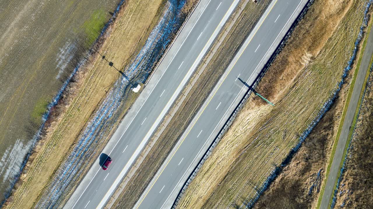 프레임을 통과하는 자동차와 함께 겨울에 고속도로의 머리 위 드론 샷