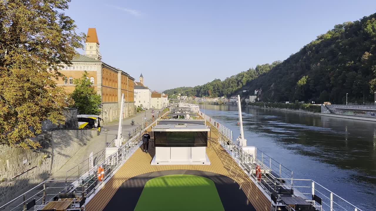 Sunrise and docked cruise ship on river Danube, viewing over deck towards town and town hall tower, Passau, Germany