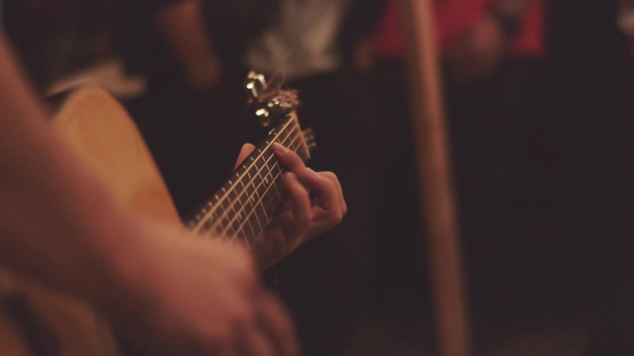 Close-up of Hands Playing Acoustic Guitar in Warm Light