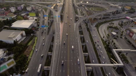 aerial view of highway road interchange with busy urban traffic speeding on road