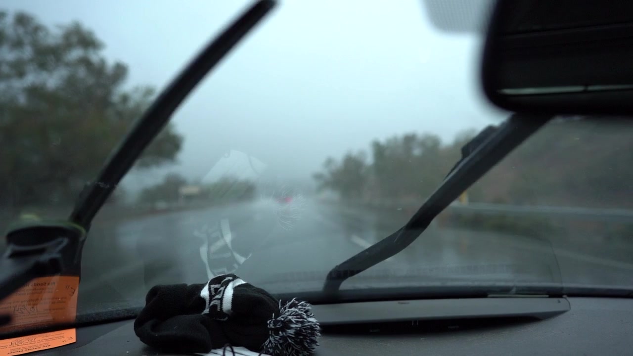 Raindrops fall on car windshield - driving