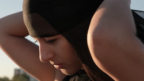 young woman covering her hair with black shawl, close up