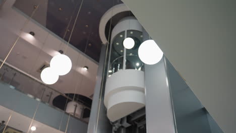 first-person view capturing an elevator with modern design and round light fixtures in the background. the camera focuses on the sleek architectural elements and illuminated spheres