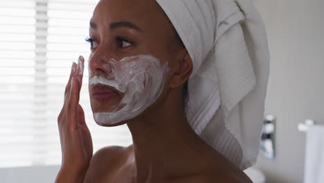 close up of african american woman applying face mask in the bathroom