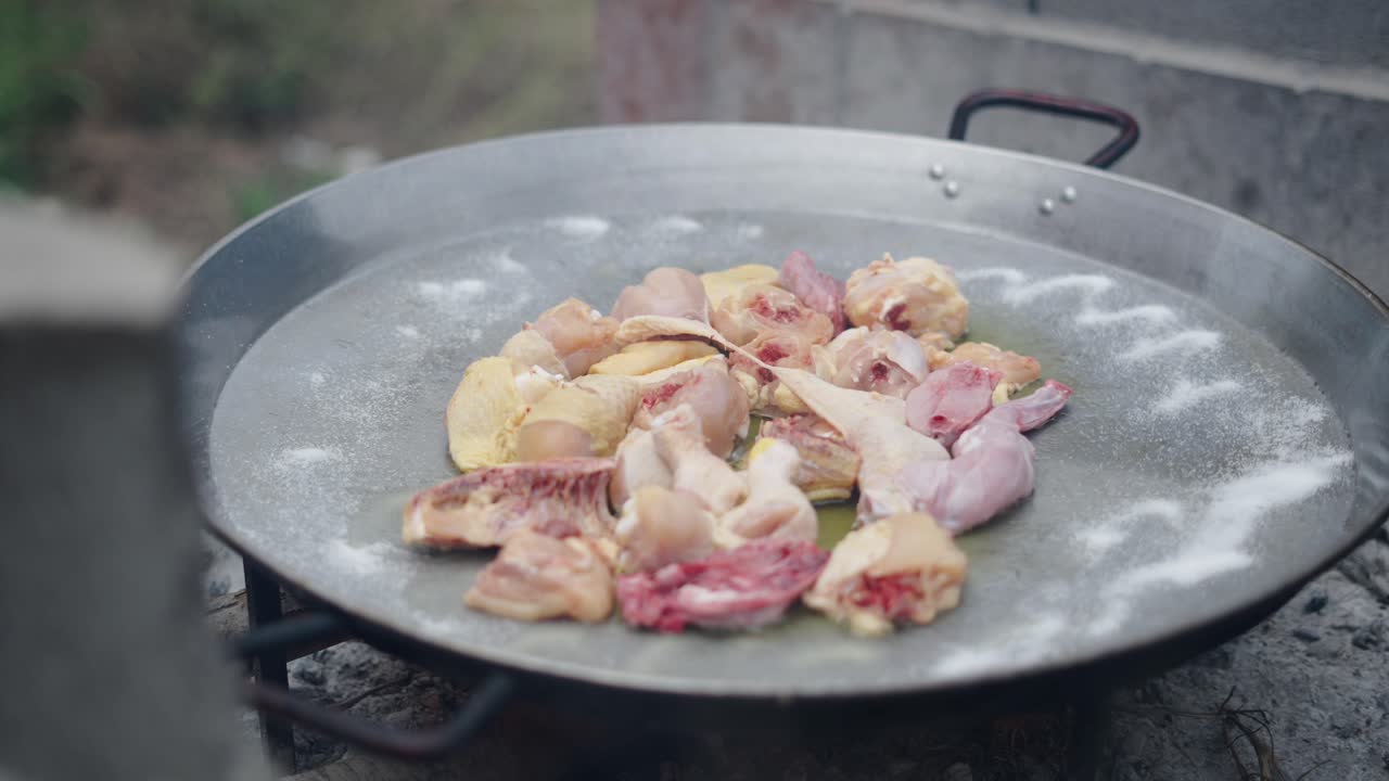 Preparing raw chicken in a large pan for cooking