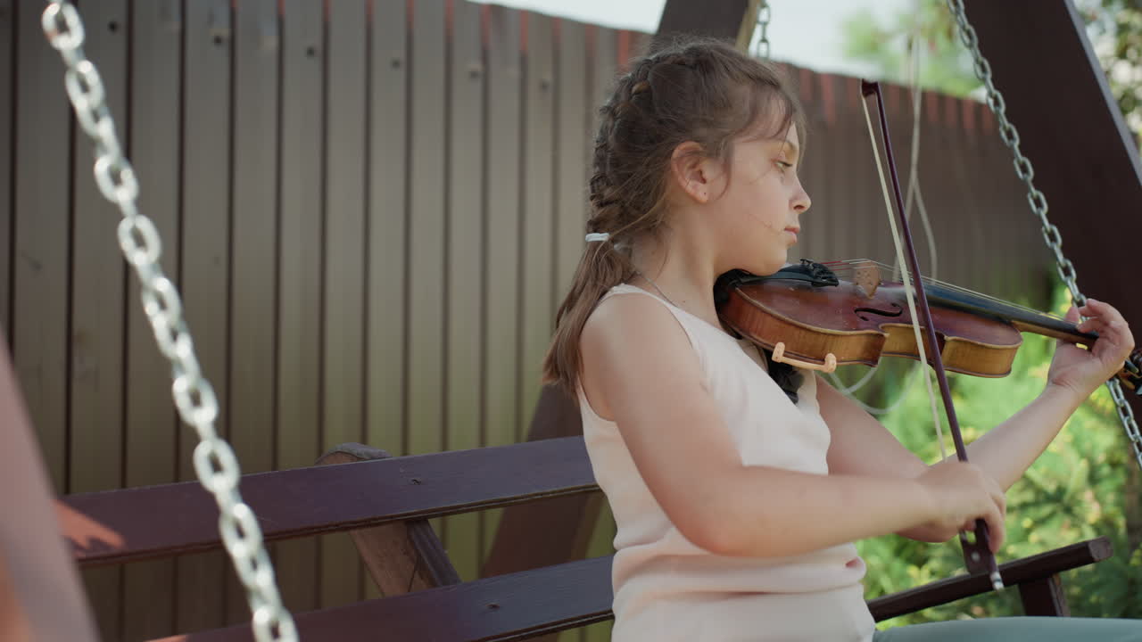 Girl Practicing Violin Outdoors Happily, Teenage Girl Enjoying Violin In Garden Environment, Casual Scene Of Teenage Girl Gracefully Practicing Her Violin Among Vivid Green Plants And Flowers