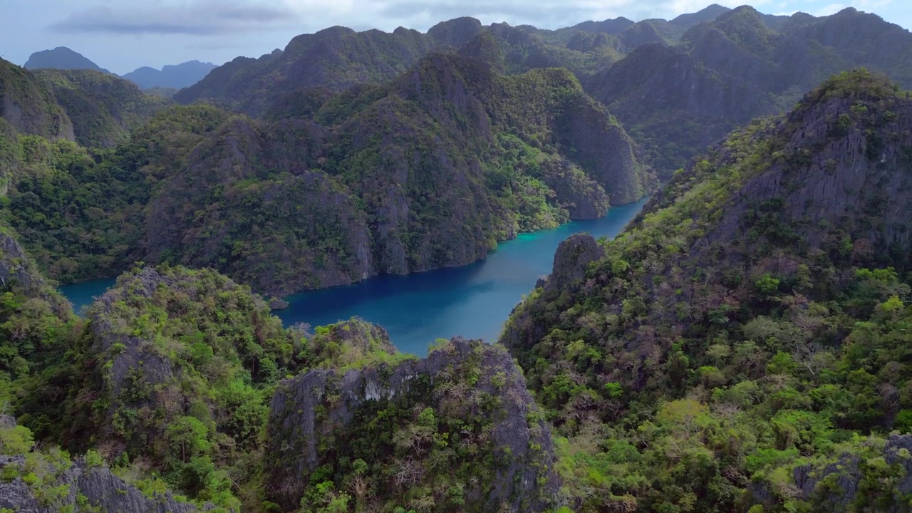 Água turquesa do Lago Kayangan de uma lagoa escondida cercada por imponentes carstes de calcário cobertos por vegetação verde exuberante. Vista aérea suave, panorama de drone ascendente.