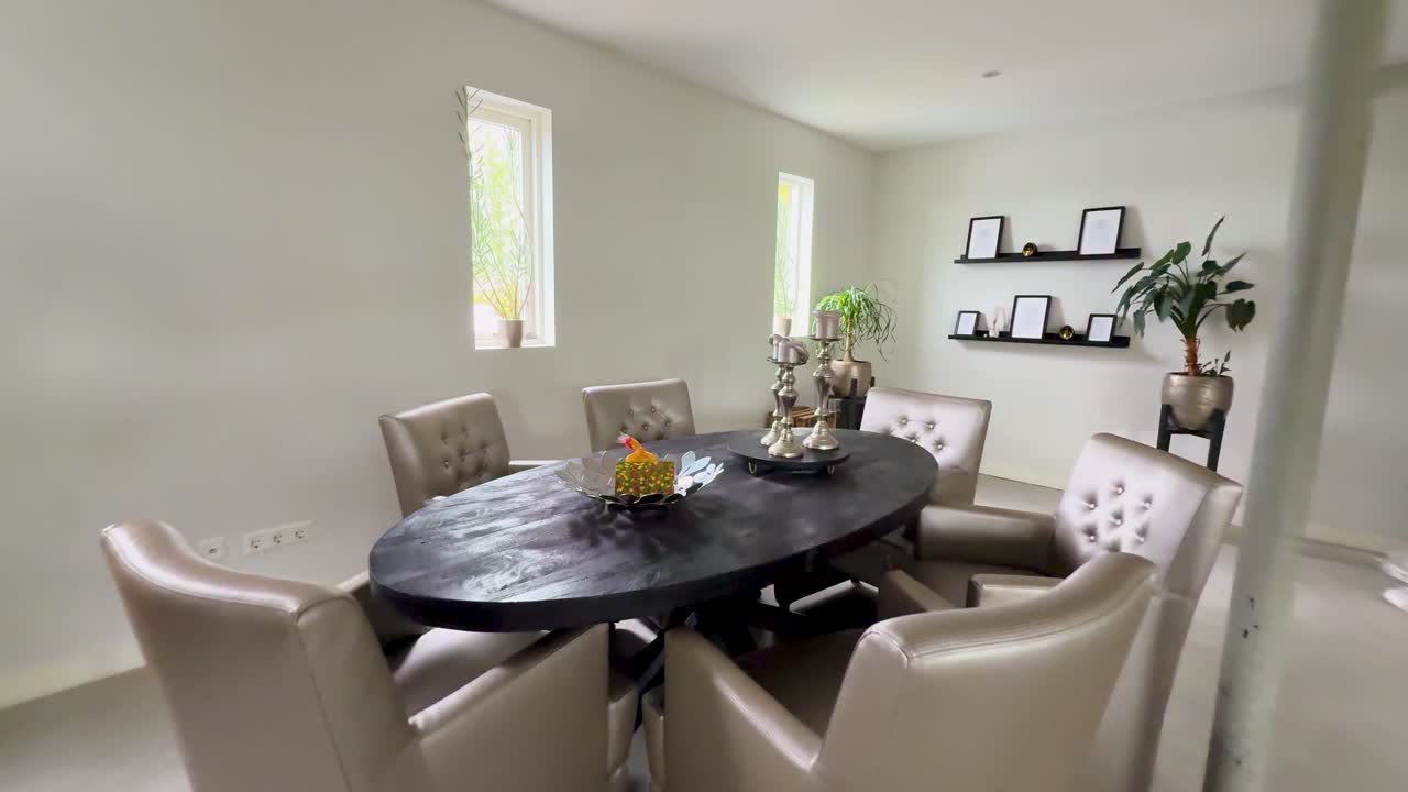 Camera moves forward through a bright, modern dining room with elegant furniture and plants